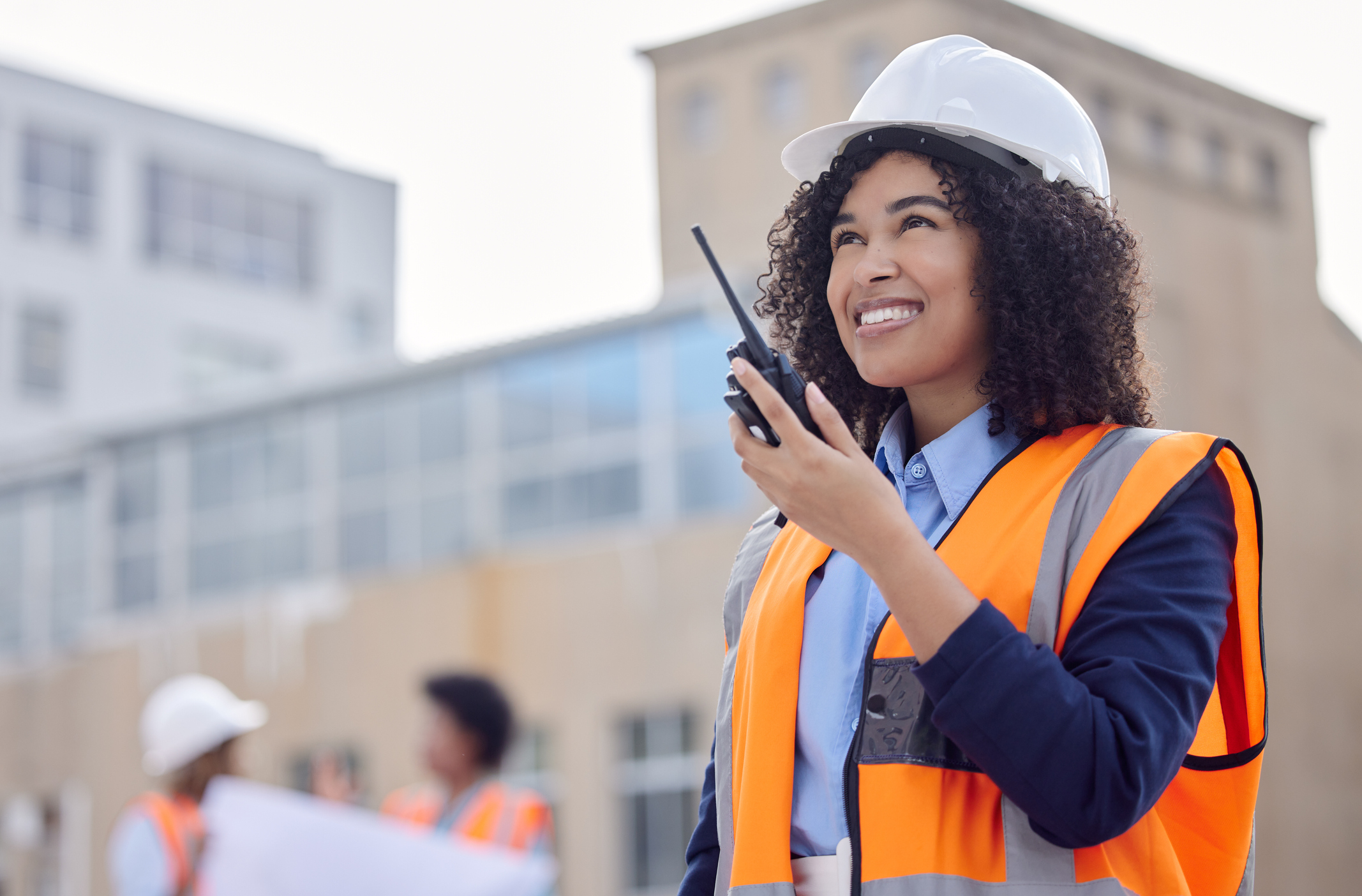 Construction worker, woman with walkie talkie and communication, engineering and architect at work site. Inspection, technology and happy female contractor, building industry and labor outdoor